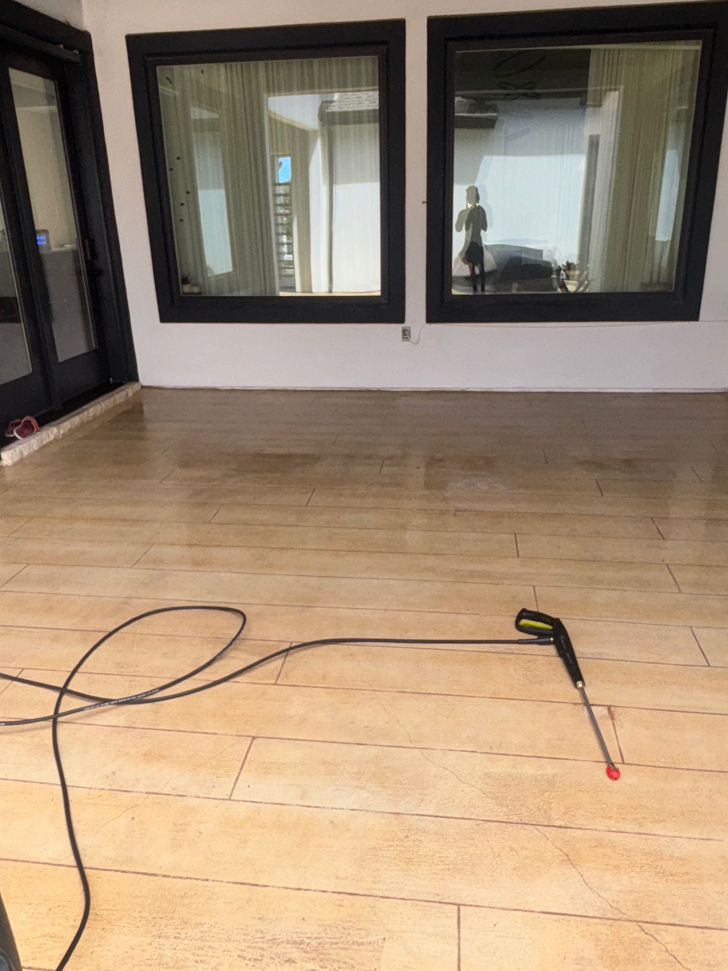 Patio tiles freshly pressure washed, with the cleaning lance resting on the stone
