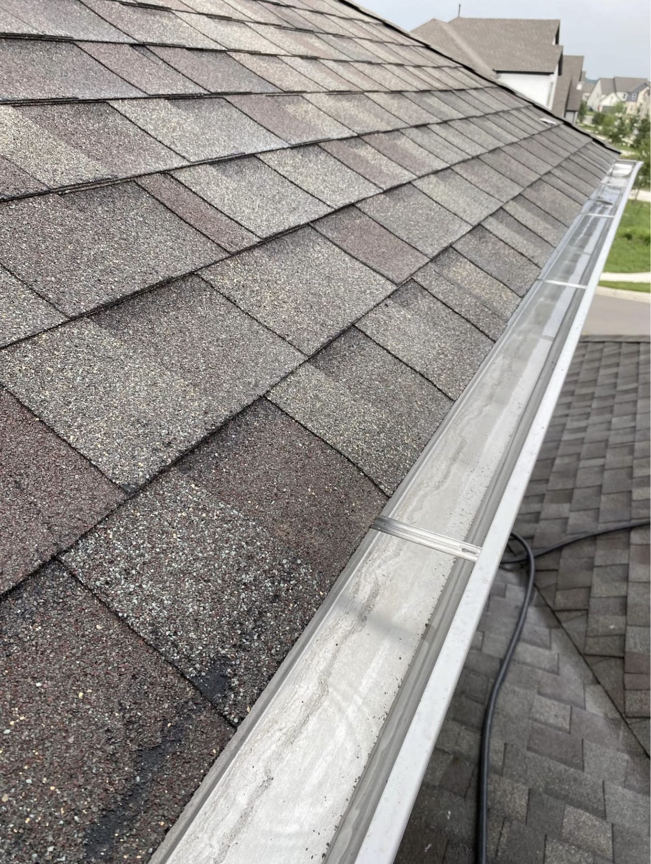 A roof gutter freshly cleared and cleaned along the shingles